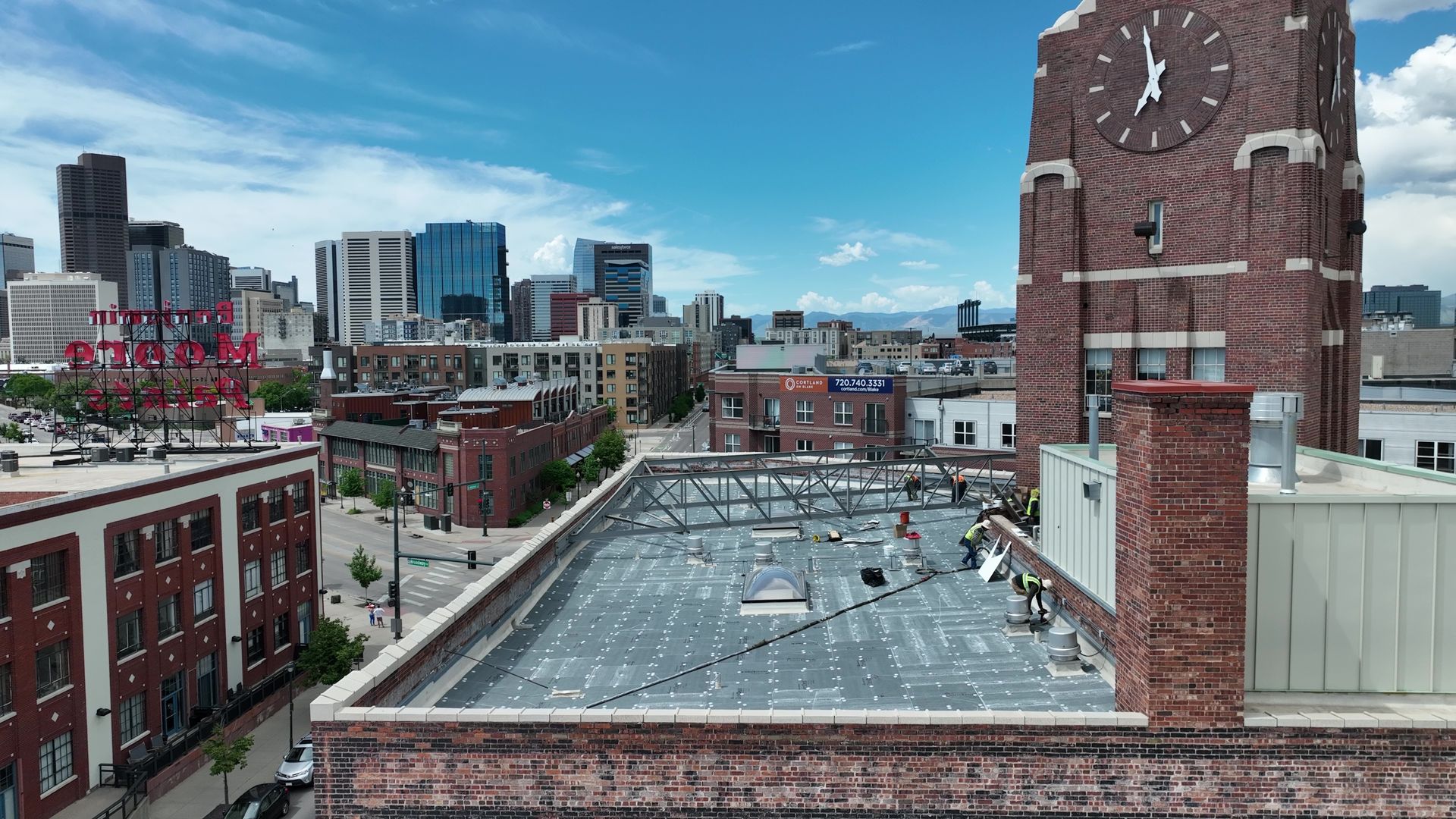 Formula Roofing crew working on historic building with Denver skyline in background